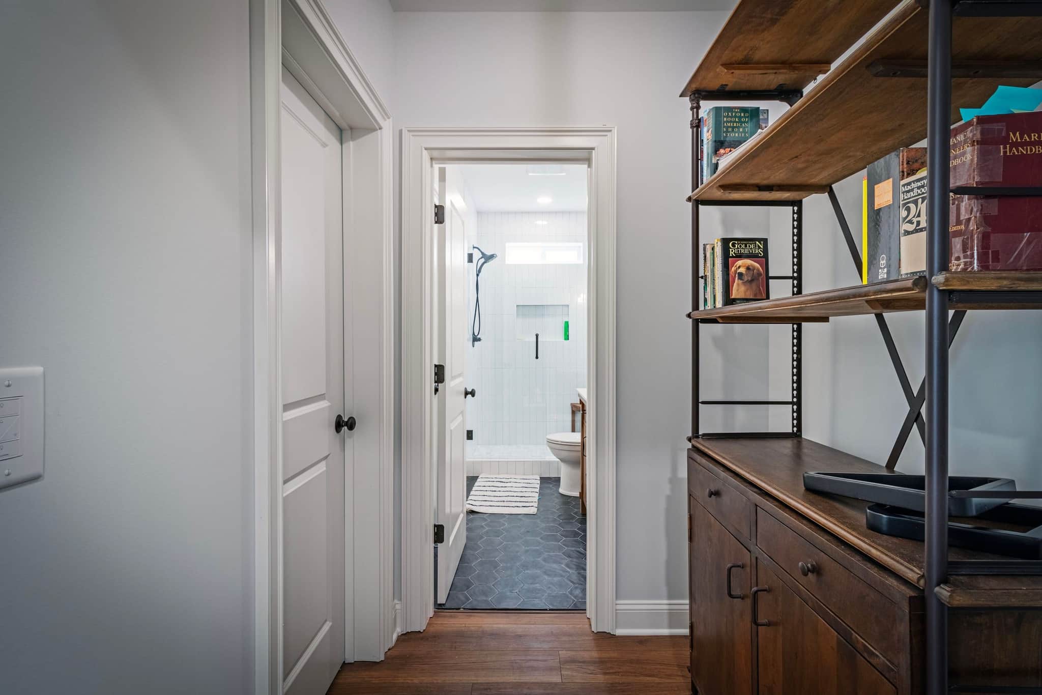 Hallway opening to a tiled walk-in shower with hex floor tile