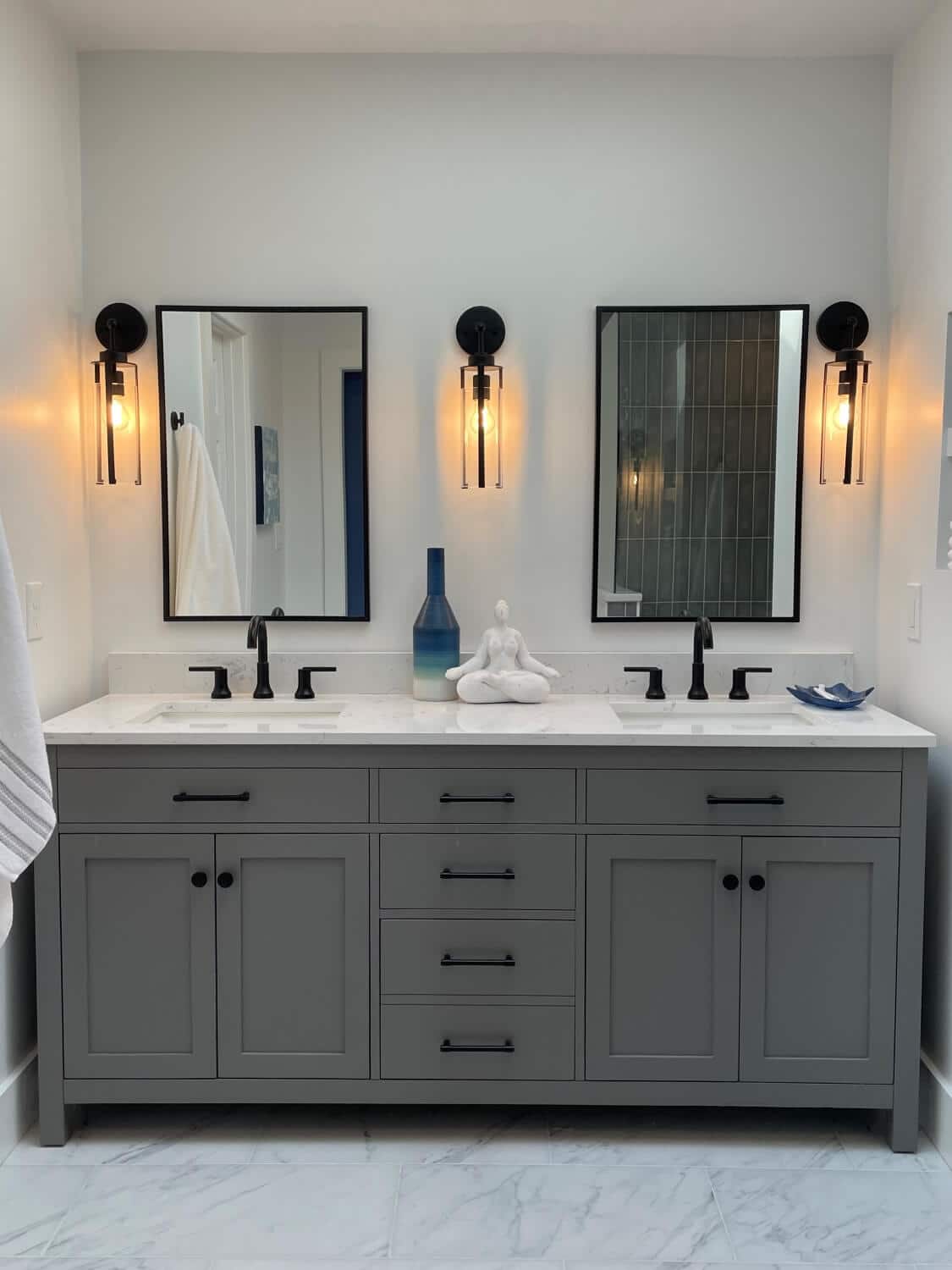 Modern double-vanity bathroom with gray cabinetry, black fixtures and glass sconces