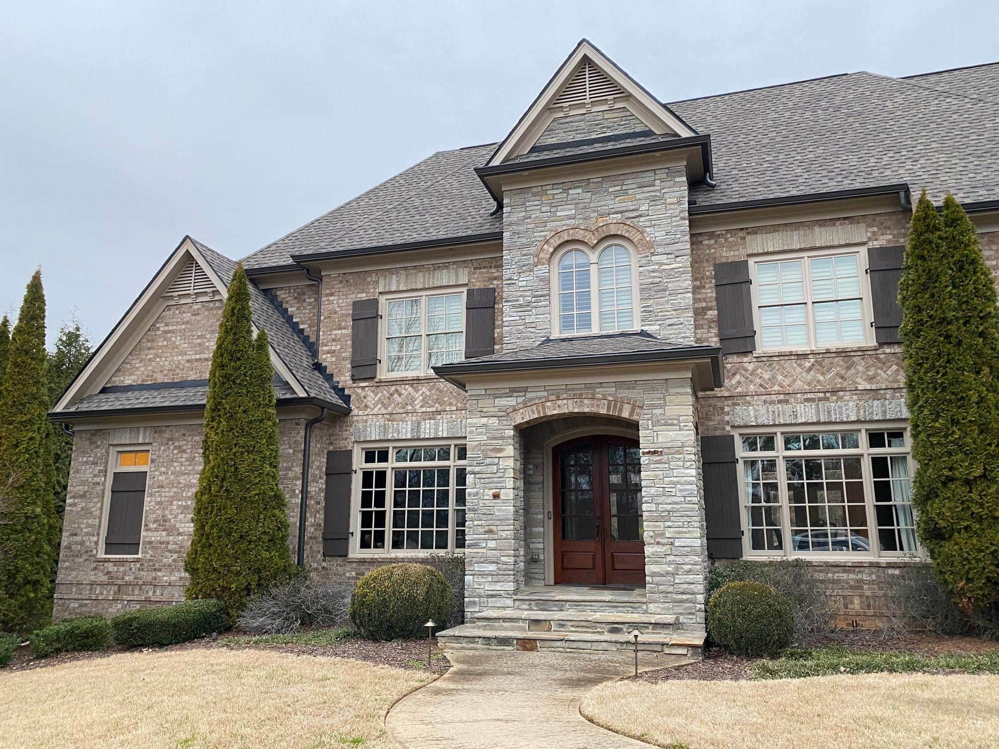 Custom stone-and-brick home with arched entry and gabled roofline