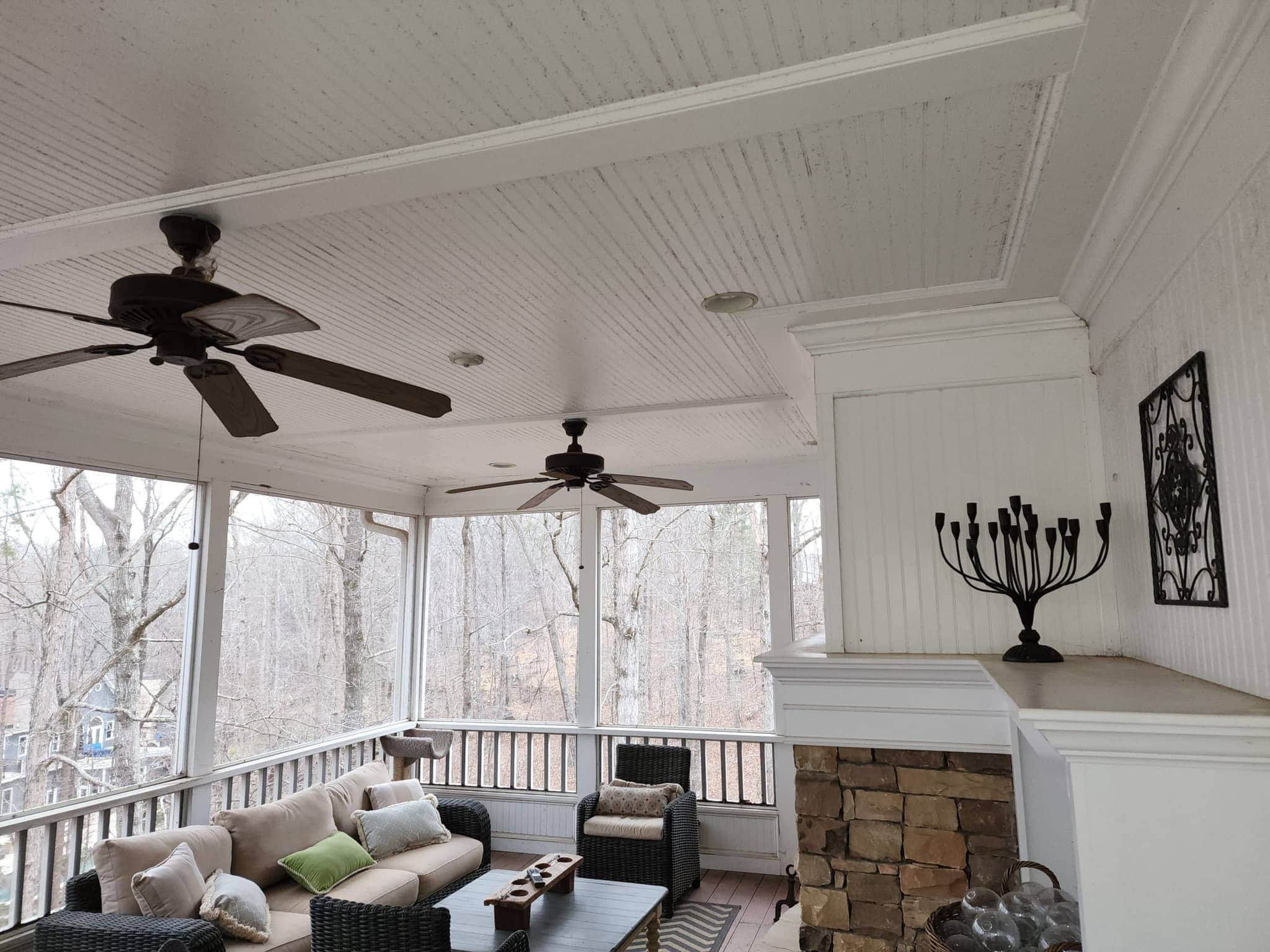 Screened porch with stacked-stone wood-burning fireplace and wicker seating