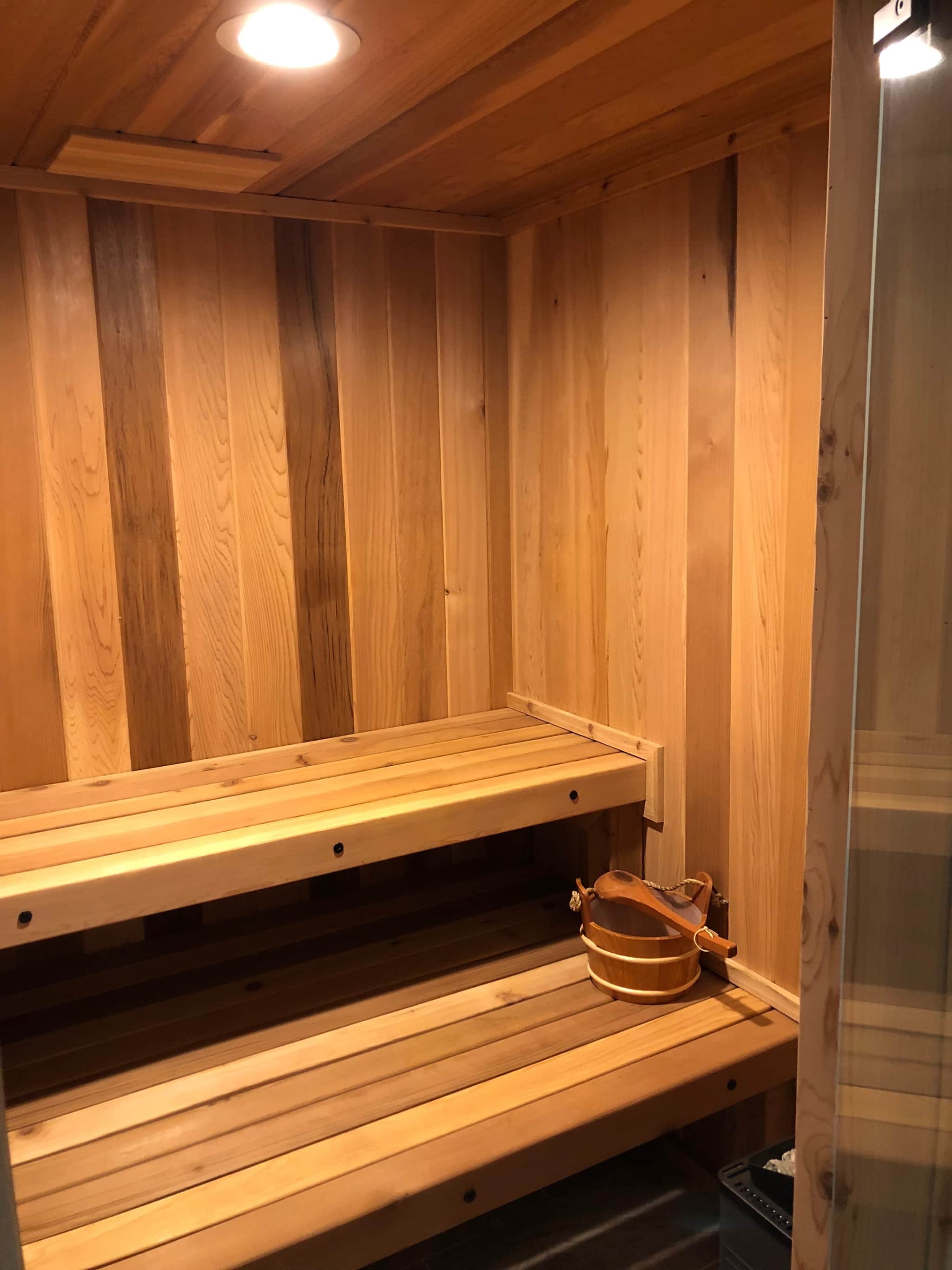 Cedar-lined home sauna with tiered bench seating and a glass door