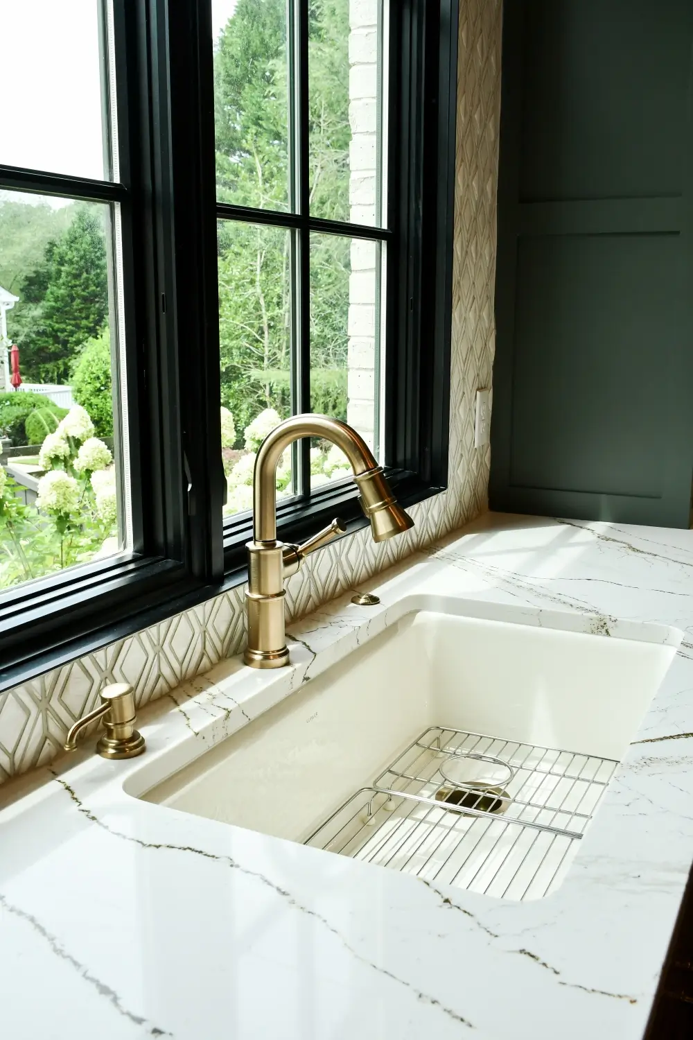 Kitchen detail with brushed-gold faucet, marble countertop and diamond-pattern tile backsplash