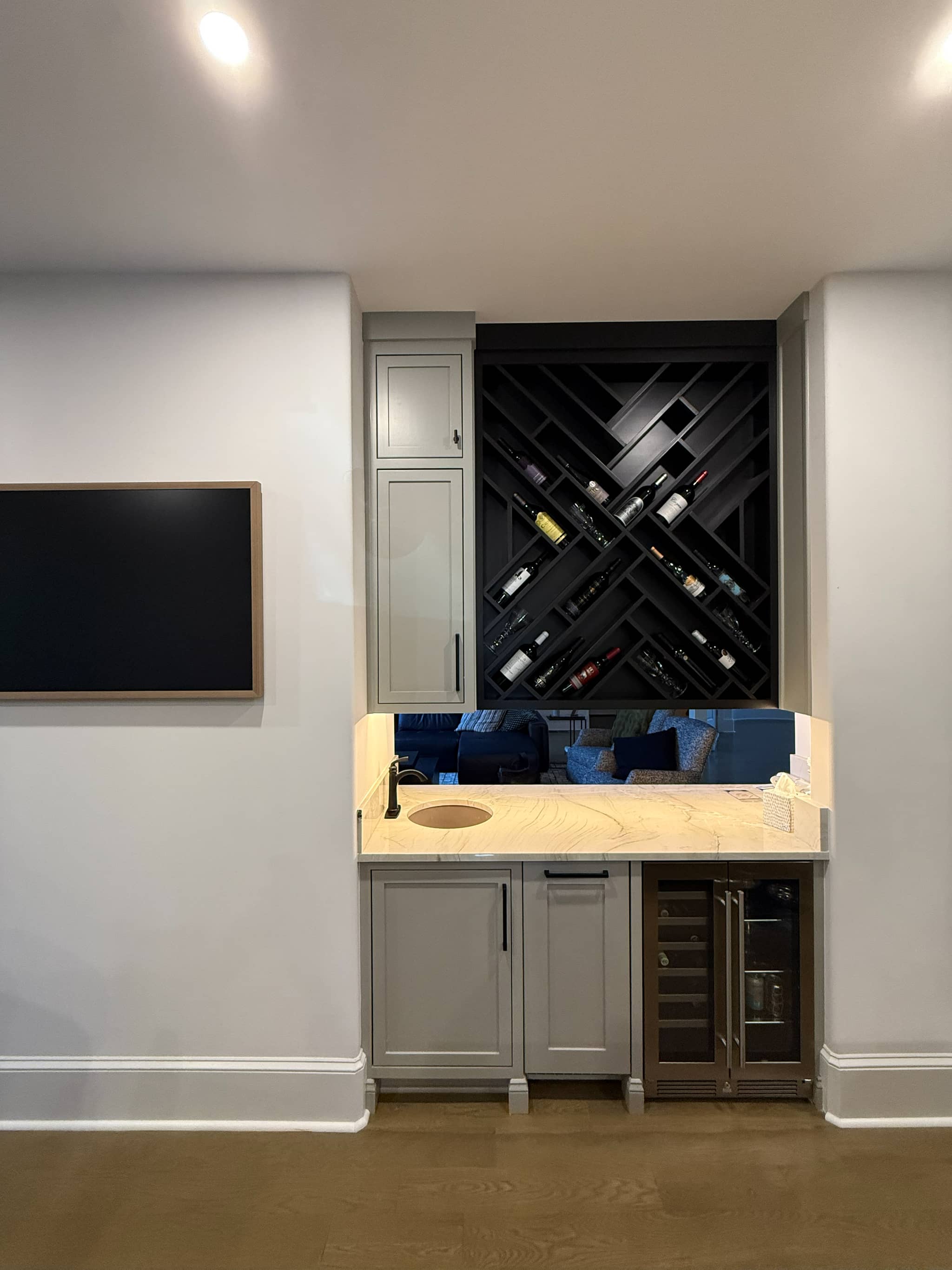 Basement wet bar with grey cabinets, a lattice wine rack, a marble counter and a beverage fridge