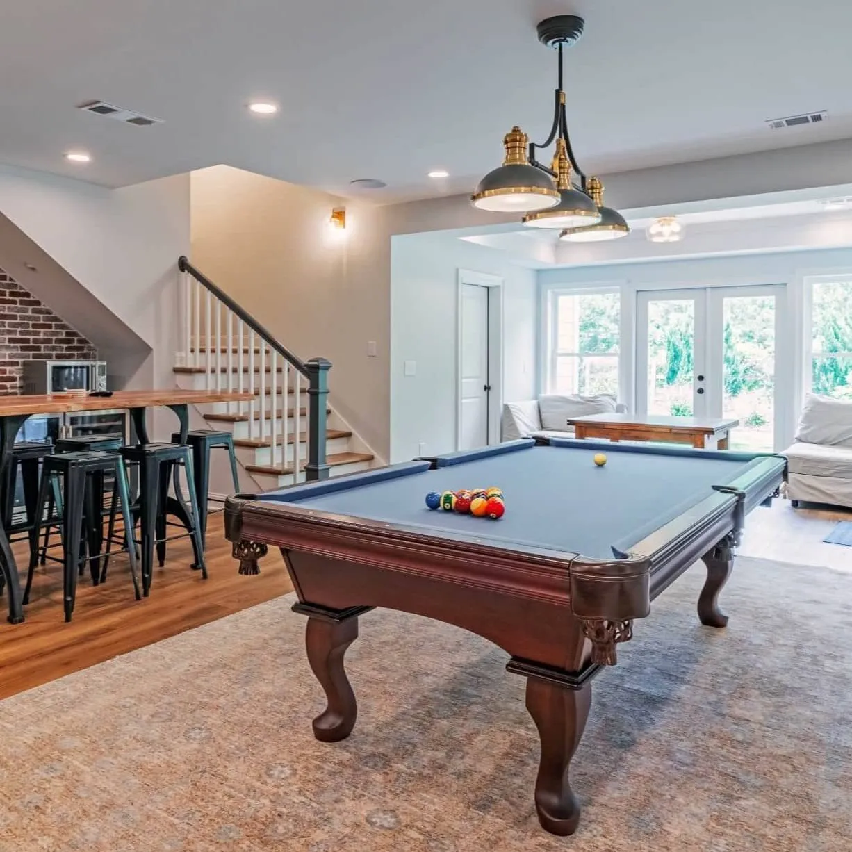 Basement game room with a pool table, a brick bar with stools and French doors to the yard