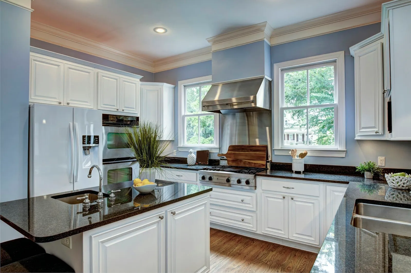 Traditional kitchen with white raised-panel cabinets, dark granite counters and a stainless range hood
