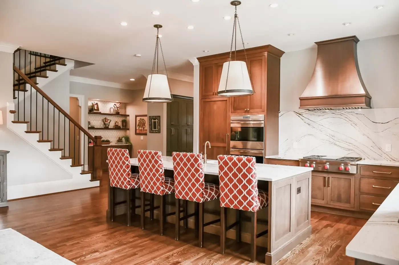 Kitchen with cherry cabinets, a copper range hood, a marble backsplash and patterned barstools