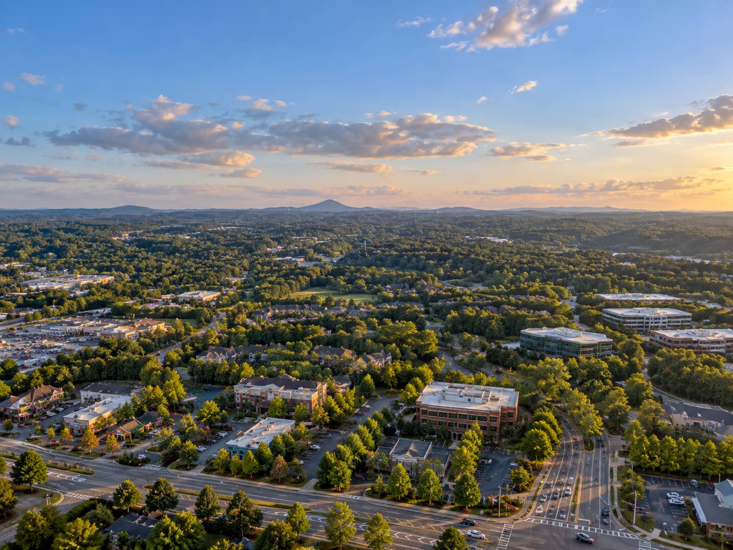 Aerial view over Johns Creek office parks and wooded neighborhoods at sunset