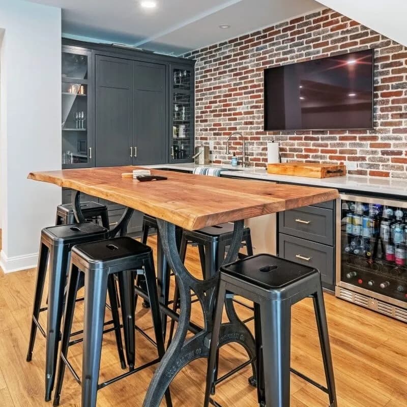 Basement bar with an exposed brick wall, a live-edge bar top, black stools and a beverage fridge